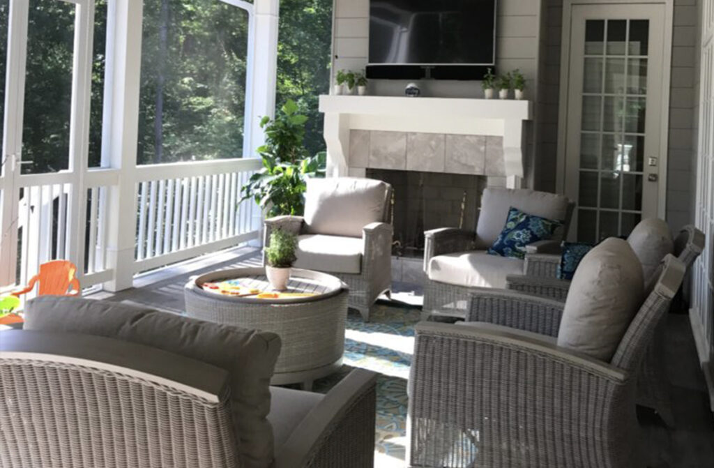 Screened-in porch with wicker chairs, sofa, round wicker coffee table, and stone fireplace.
